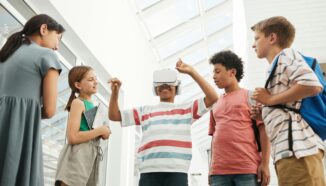 Leerlingen in een lichte schoolomgeving testen een VR-bril terwijl klasgenoten nieuwsgierig toekijken.